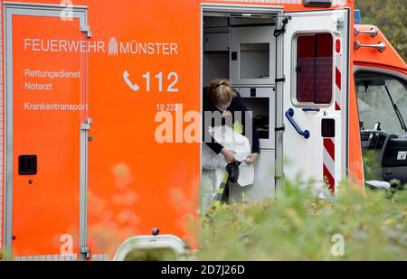 23. Oktober 2020, Nordrhein-Westfalen, Münster: Ein Sanitäter zieht einen Schutzanzug an, um einen Corona-Patienten in das Universitätsklinikum Münster zu transportieren. Der Transfer soll den Druck auf die Intensivstationen verringern. Die Niederlande gehören zu den am stärksten betroffenen Ländern in Europa. Foto: Caroline Seidel/dpa Stockfoto