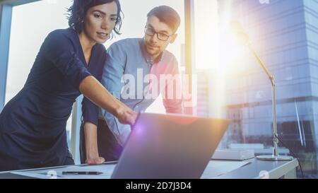 Junge vielversprechende Geschäftsmann und Geschäftsfrau diskutieren ihre Startup-Projekt und mit Laptop. Neue Generation intelligenter junger Menschen in Unternehmen. So Stockfoto