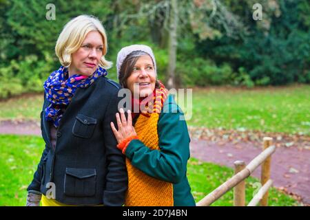 Zwei Frauen in ihren 50ern umarmten sich und lächelten Im Park im Herbst Stockfoto