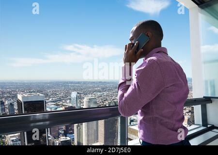 Afrikanischer Mann mit Blick auf die Innenstadt auf EINEM Balkon