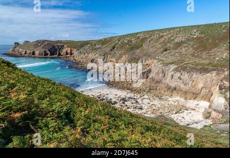 Blick auf die Brandung, die in Nanjizel oder Mill Bay mit Carn Boel, Cliff, Coast Path, und entfernten Longships Leuchtturm; Cornish Coast in der Nähe Lands End. Mi Stockfoto