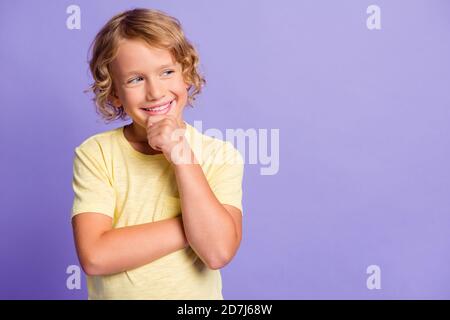 Foto von gesinnten Kind berühren Finger Gesicht suchen leeren Raum Denken Gedanken tragen gelbe T-Shirt isoliert über lila Farbe Hintergrund Stockfoto