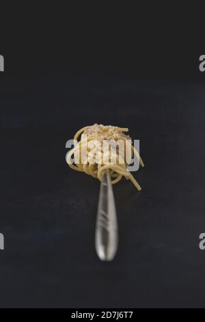 Gabel von traditionellen italienischen Gericht Spaghetti Carbonara isoliert auf dunklem Hintergrund. Nahaufnahme. Stockfoto