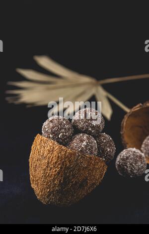 Kokosnuss gesunde zuckerfreie Glückseligkeit Bälle in Kokosnussschalen auf dunklem Hintergrund platziert. Nahaufnahme. Stockfoto