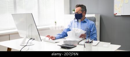 Ältester Geschäftsangestellte, Der Bei Computer Wearing Facial Mask Arbeitet Stockfoto