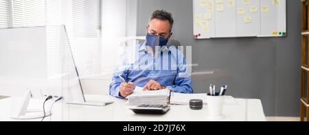 Ältester Geschäftsangestellte, Der Bei Computer Wearing Facial Mask Arbeitet Stockfoto