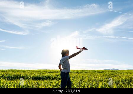 Sorgloser Junge, der mit Flugzeugspielzeug gegen klaren Himmel spielt Stockfoto
