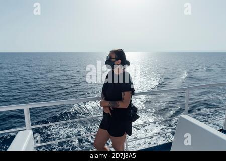 Frau trägt Gesichtsmaske stehen durch Geländer von Passagierschiff Stockfoto