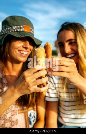 Fröhliche junge Frauen, die Eiszapfen rösten, während sie das Wochenende genießen Gemeinsam Stockfoto