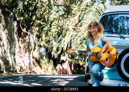 Reife Frau trägt Sonnenbrille Gitarre spielen, während Sie am Motor stehen Zuhause auf der Straße Stockfoto