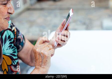 Nahaufnahme einer älteren Frau mit Smartphone am Tisch Hof Stockfoto