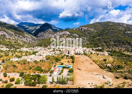 Luftaufnahme des Dorfes in der Nähe von Bergen gegen bewölkten Himmel an sonnigen Tagen, Caimari, Mallorca, Spanien Stockfoto