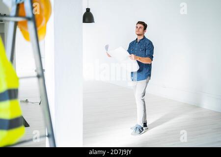 Architekt mit blauem Druck, während er auf der Baustelle steht Stockfoto