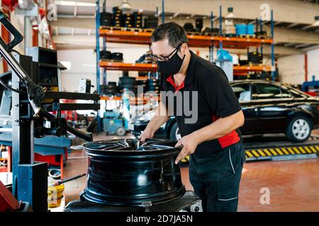 Mechaniker trägt Maske während der Arbeit in Auto-Werkstatt Stockfoto