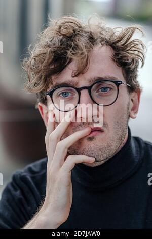 Nahaufnahme des traurigen jungen Mannes, der draußen sitzt Stockfoto