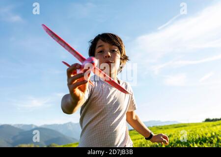 Junge spielt mit Flugzeug Spielzeug, während sie gegen klaren Himmel stehen Stockfoto