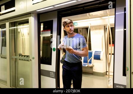 Ein hübscher junger Pendler schaut weg, während er von der U-Bahn aussteigt Zug am Bahnhof Stockfoto