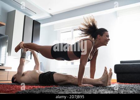 Mann, der das Bein der Frau hält, während er zu Hause auf dem Teppich liegt Stockfoto