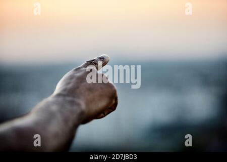 Von der Terrasse aus auf den Himmel zeigende, beschnittene Hand des Mannes Bei Sonnenuntergang Stockfoto