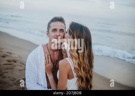 Junge Frau küsst Mann, während sie am Strand steht Stockfoto