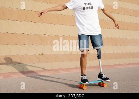 Junger Mann mit künstlichem Bein und Fuß auf dem Skateboard stehend Auf dem Sportplatz Stockfoto