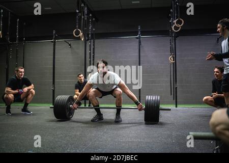 Athlet jubelnden Mann hocken, während Hantel im Fitnessstudio heben Stockfoto