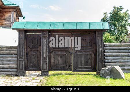 Verwittertes Tor mit grünem Dach und Zaun in der Nähe von ländlichen Haus Stockfoto