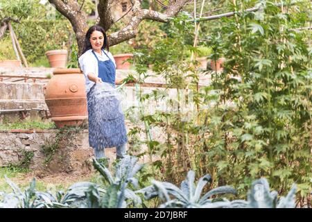 Frau im Garten beim Bewässern aus Schlauch im Gemüsegarten Stockfoto