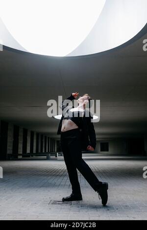 Nicht-binäre junge Mann tanzen auf dem Boden unter beleuchtetem Licht in Keller Stockfoto