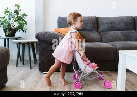 Baby Mädchen spielen mit Spielzeug und Baby Kinderwagen zu Hause Stockfoto