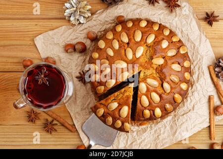 Hausgemachter Kuchen mit Mandeln und Glas mit Glühwein auf einem Holztisch. Draufsicht. Stockfoto