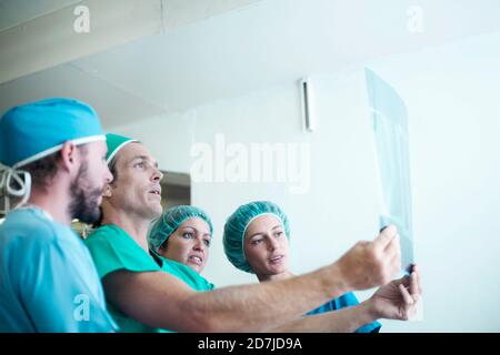 Team von männlichen und weiblichen medizinischen Mitarbeitern über Röntgenaufnahmen diskutieren Bild im Krankenhaus Stockfoto