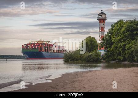Deutschland, Hamburg, Containerschiff auf Elbe und Wittenbergen Leuchtturm bei Sonnenuntergang Stockfoto