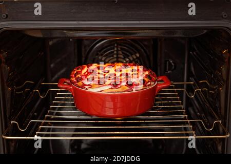 Hausgemachtes Gebäck. Hüttenkäse und Kirsche Käsekuchen in roter Keramik Bogen im heimischen Ofen gekocht. Geringer Fokus. Stockfoto