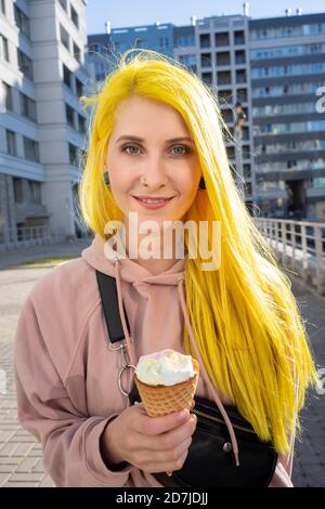 Junge Frau, die auf der Straße steht und Eis isst In der Stadt während des sonnigen Tages Stockfoto