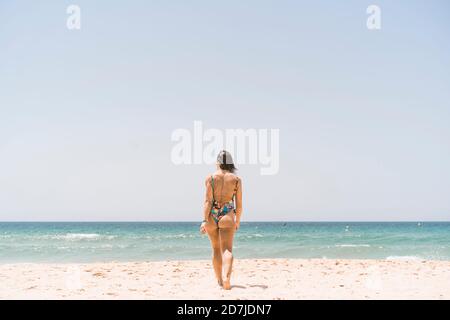 Frau mit Body beim Spaziergang am Strand von Valdevaqueros in Tarifa, Spanien Stockfoto