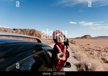 Spanien, Navarra, Porträt einer touristischen Frau, die sich aus dem Autofenster lehnt und ein Friedenszeichen in Richtung Kamera macht Stockfoto