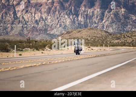 Mann, der Motorrad auf der Autobahn gegen Berg, Nevada, USA, reitet Stockfoto