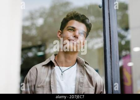 Nachdenklicher, hübscher Mann, der vom Fenster aus gesehen wegschaut Stockfoto