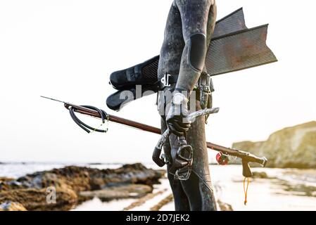 Mann mit Tauchmaske und Harpune, während er am Strand steht Stockfoto