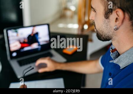Junger Mann mit Laptop während des Studiums zu Hause Stockfoto