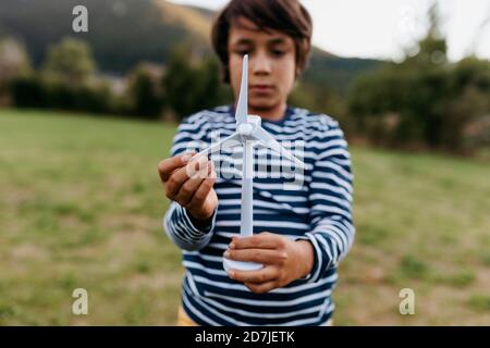 Junge spielt mit Windturbine, während er im Hinterhof steht Stockfoto