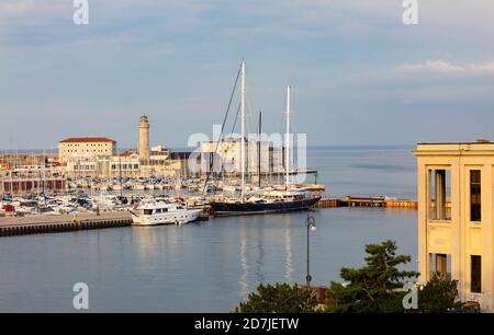 Italien, Friaul Julisch Venetien, Triest, Boote in San Giusto Sea Centre Marina mit La Lanterna Leuchtturm im Hintergrund Stockfoto