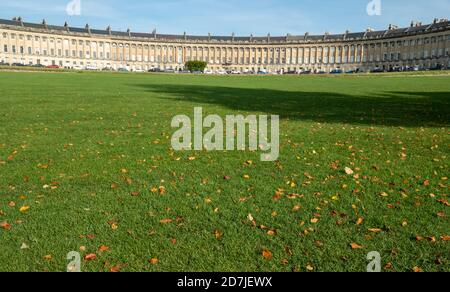 Das Royal Cresent, ein Wahrzeichen im Stadtzentrum von Bath, wurde im palladianischen Stil von John Wood entworfen. Fotografiert im Herbst mit Rasen und gefallenen Blättern. Stockfoto