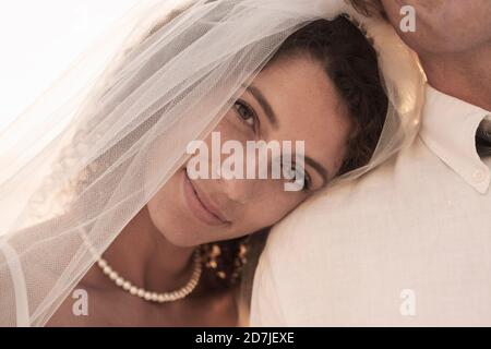 Schöne Braut im Hochzeitskleid lehnt auf der Schulter des Bräutigams Stockfoto