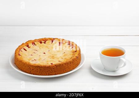 Hausgemachte Pflaumenkuchen und Tasse Tee auf weißem Holztisch. Copyspace. Stockfoto