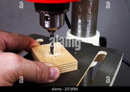 Arbeiter bohrt ein Loch in Sperrholz auf einer Bohrmaschine Stockfoto