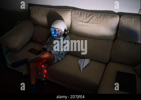 Junge trägt Raum Helm sitzen mit beleuchteten Beleuchtung Ausrüstung an Sofa zu Hause Stockfoto