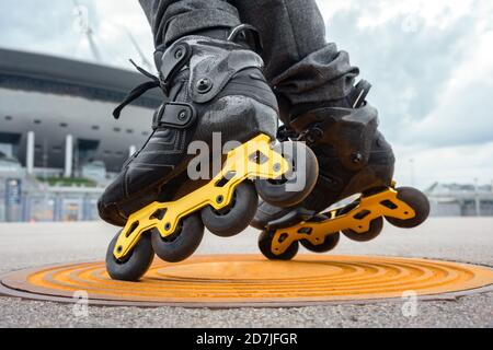 Beine von jungen Mann Inline-Skating auf Mannloch Stockfoto