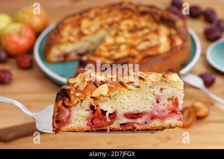 Nahaufnahme Stück hausgemachten Kuchen mit Äpfeln und Pflaumen mit Mandelblättern. Geringer Fokus. Stockfoto